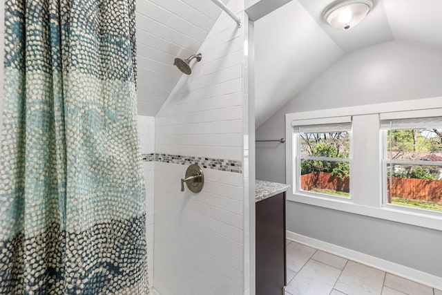 full bath with lofted ceiling, baseboards, marble finish floor, and tiled shower