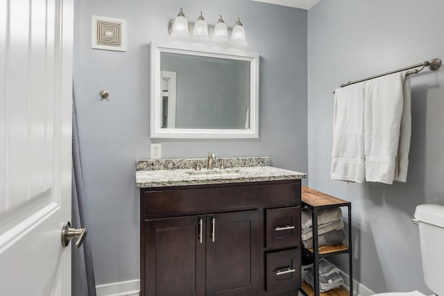 bathroom featuring toilet, visible vents, baseboards, wood finished floors, and vanity
