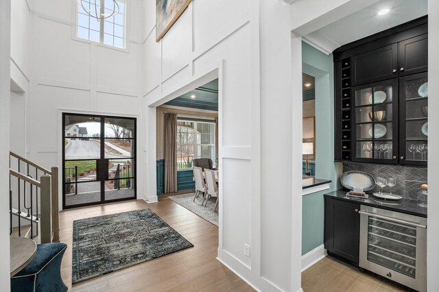 7247 Murrel Dr, Franklin, TN 37064 - bar with stairs, beverage cooler, a towering ceiling, and light wood-style flooring