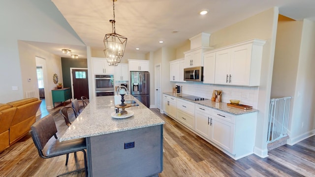 kitchen featuring tasteful backsplash, wood finished floors, a breakfast bar, stainless steel appliances, and white cabinets