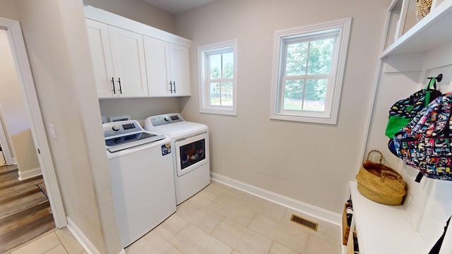 laundry room featuring light tile patterned flooring, washer and dryer, cabinet space, baseboards, and visible vents