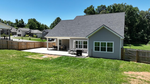 rear view of property featuring a patio area, a lawn, a shingled roof, and a fenced backyard
