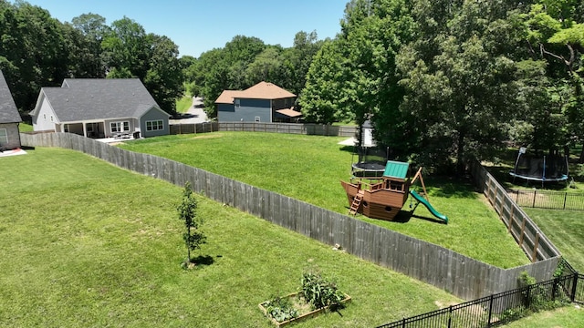 view of yard with a trampoline, a fenced backyard, and a playground