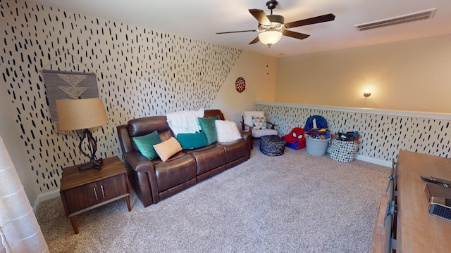 living room featuring a ceiling fan, wallpapered walls, carpet, baseboards, and visible vents