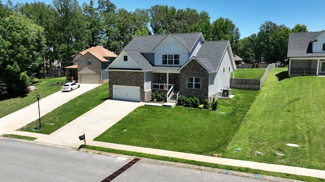 view of front facade with central AC, concrete driveway, board and batten siding, stone siding, and a front yard