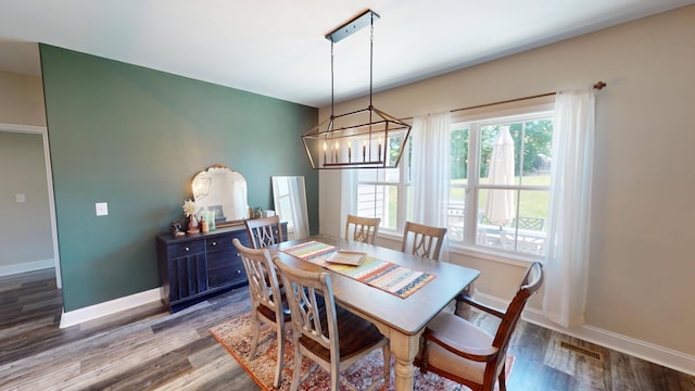 dining space with dark wood-type flooring, baseboards, and an inviting chandelier