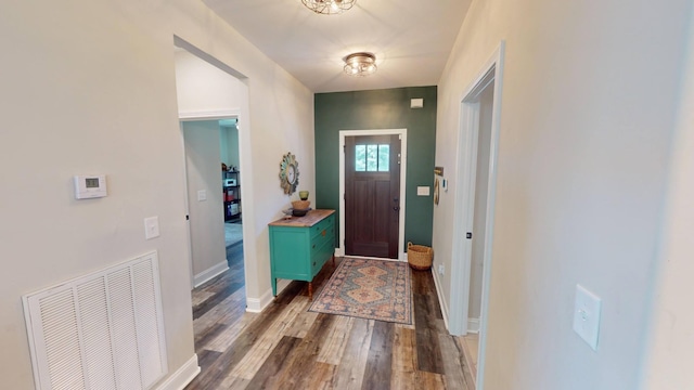 foyer entrance with baseboards, wood finished floors, and visible vents