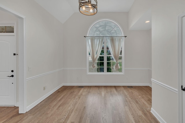 unfurnished dining area with a chandelier, lofted ceiling, a healthy amount of sunlight, and light wood-type flooring