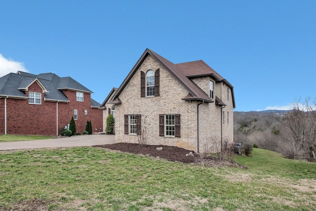 exterior space with brick siding, a yard, and driveway