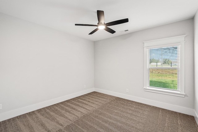 carpeted empty room with baseboards, visible vents, and ceiling fan