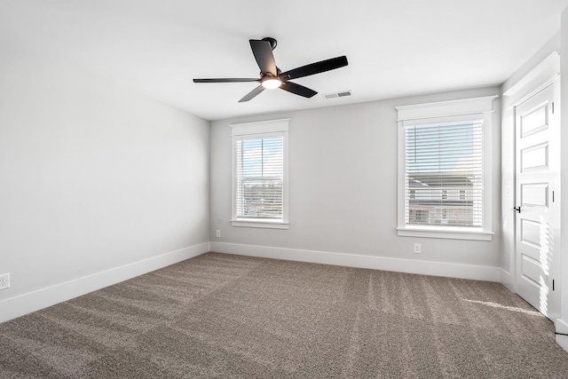 carpeted empty room with visible vents, ceiling fan, and baseboards