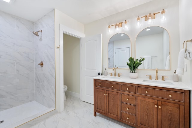 full bath featuring double vanity, toilet, tiled shower, and a sink