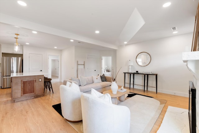 living area with visible vents, baseboards, recessed lighting, light wood-style flooring, and a premium fireplace
