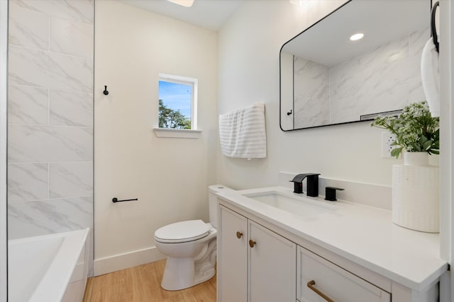 bathroom featuring vanity, toilet, a washtub, baseboards, and wood finished floors