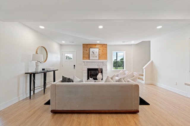 living room featuring baseboards, a stone fireplace, recessed lighting, and light wood-style flooring