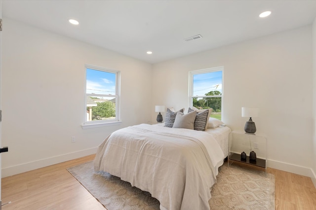 bedroom featuring visible vents, light wood-style flooring, baseboards, and multiple windows