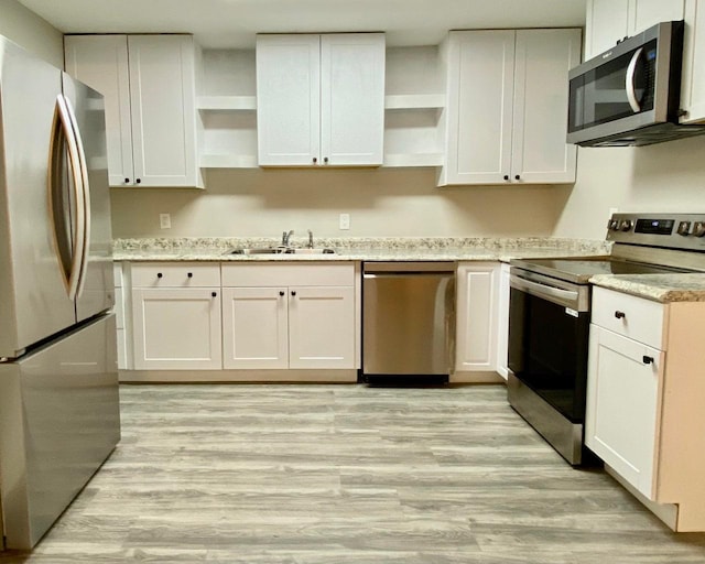 kitchen with open shelves, white cabinets, stainless steel appliances, and a sink