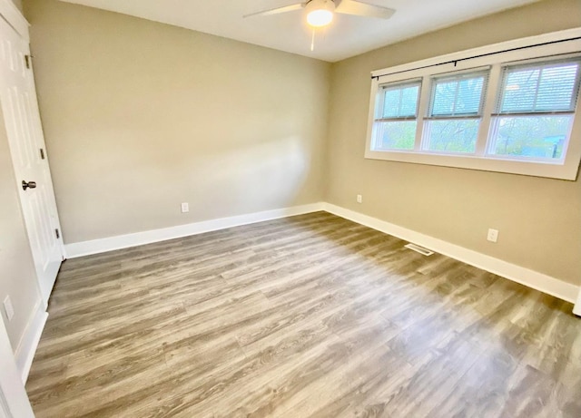 spare room with visible vents, baseboards, a ceiling fan, and wood finished floors