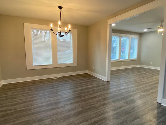 unfurnished dining area with baseboards, dark wood-style flooring, visible vents, and ceiling fan with notable chandelier