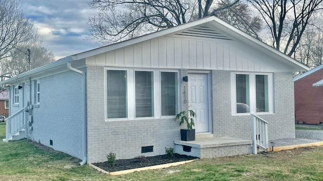 view of front of property with brick siding, crawl space, and a front yard
