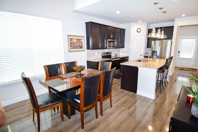 dining room featuring recessed lighting, light wood finished floors, baseboards, and an inviting chandelier