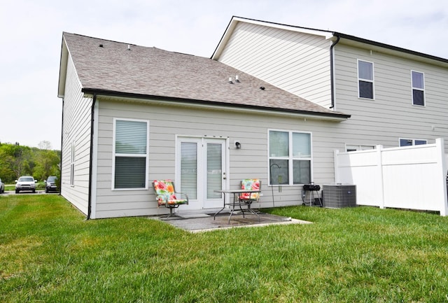 back of property with fence, central air condition unit, a patio, a lawn, and roof with shingles