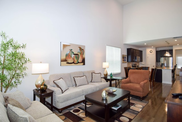 living room featuring wood finished floors, visible vents, and a high ceiling