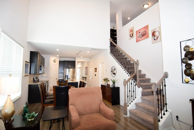 stairway with recessed lighting, wood finished floors, a high ceiling, and baseboards