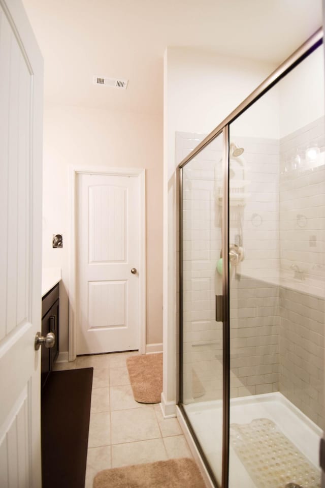 bathroom with tile patterned floors, visible vents, baseboards, a shower stall, and vanity