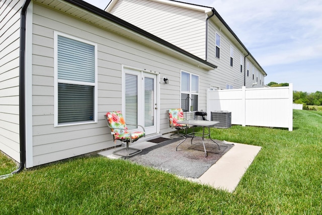 back of property featuring fence, a lawn, cooling unit, and a patio
