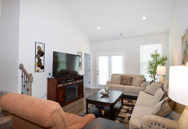 living area with baseboards, visible vents, recessed lighting, wood finished floors, and high vaulted ceiling