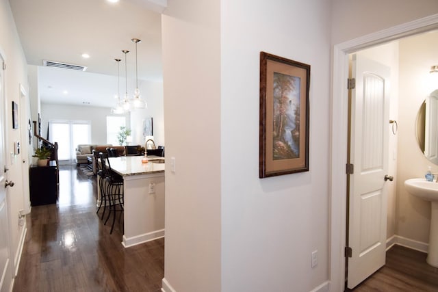 hall featuring visible vents, a sink, recessed lighting, and dark wood-style flooring