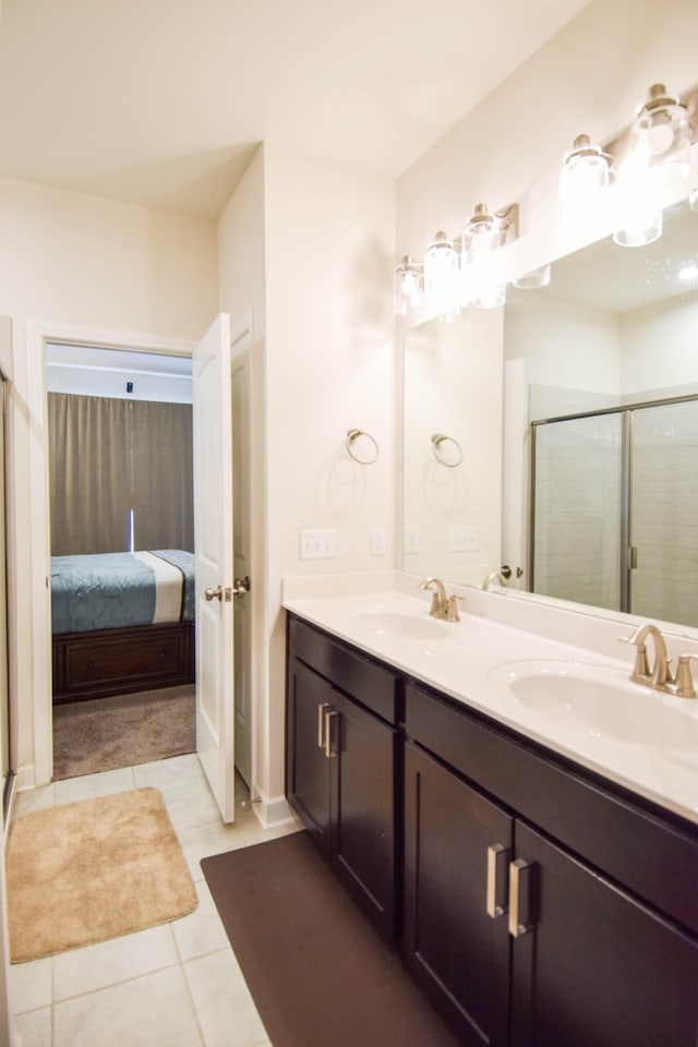 ensuite bathroom with double vanity, a shower stall, and a sink