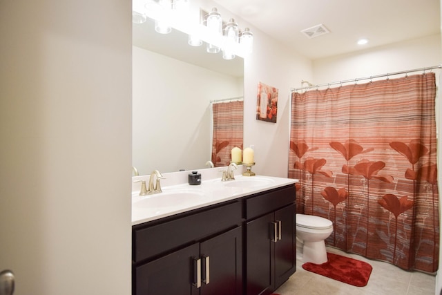 bathroom featuring toilet, tile patterned floors, a sink, and double vanity