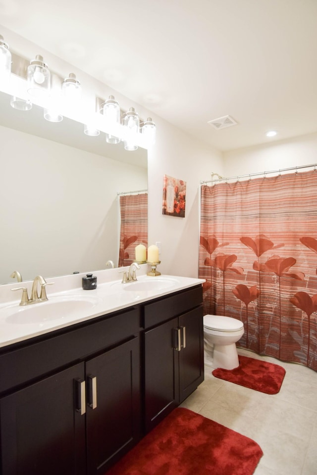 bathroom with double vanity, visible vents, toilet, and a sink