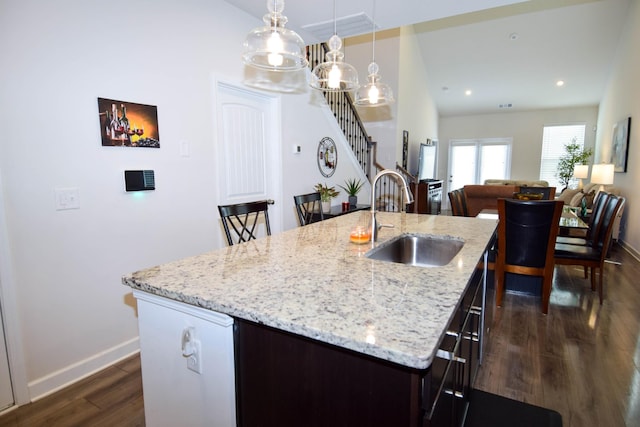 kitchen with a sink, a kitchen island with sink, baseboards, dark wood-style flooring, and visible vents