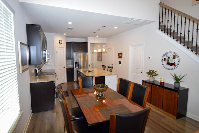dining area with a chandelier, wood finished floors, and stairs