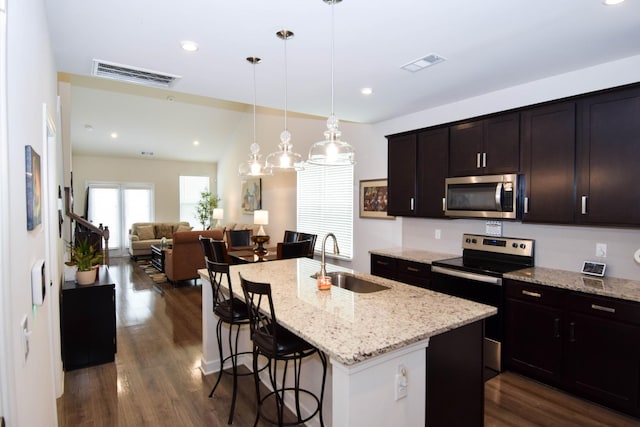 kitchen featuring stainless steel appliances, visible vents, a sink, and a breakfast bar area