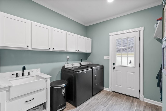 laundry room with light wood-style flooring, a sink, cabinet space, crown molding, and washer and dryer