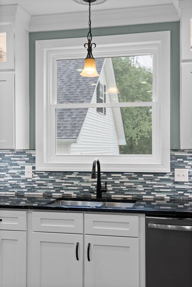 kitchen with tasteful backsplash, a sink, white cabinets, ornamental molding, and dishwashing machine