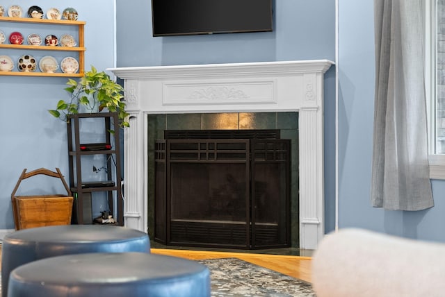 room details featuring a tiled fireplace and wood finished floors