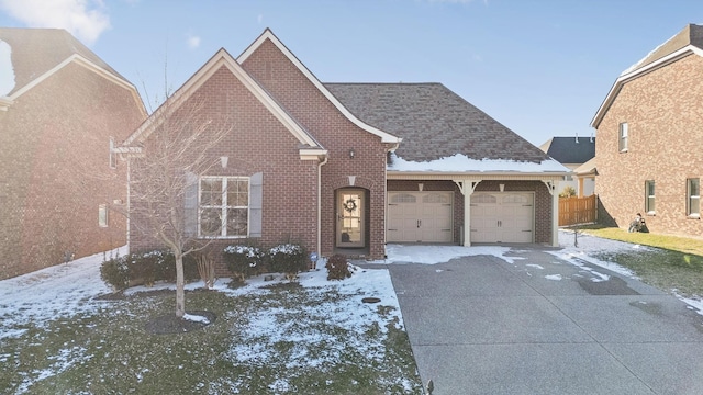view of front of house with brick siding, an attached garage, concrete driveway, and fence