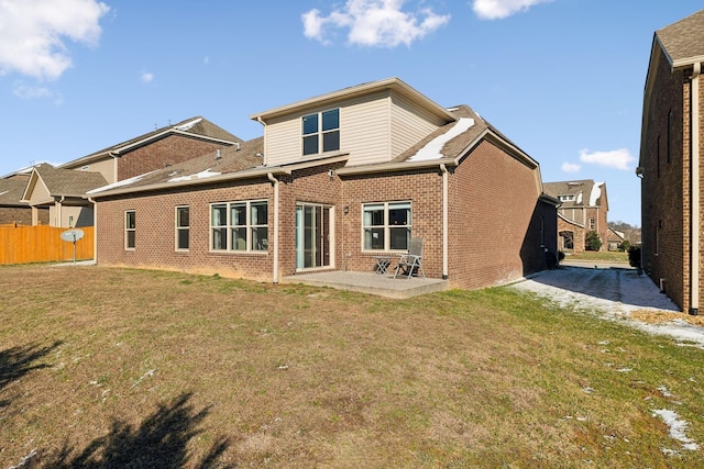 back of property featuring brick siding, a lawn, a patio, and fence