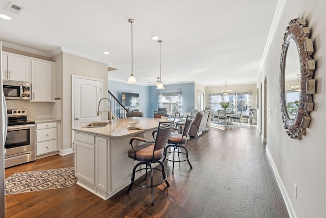 kitchen with a sink, a breakfast bar, stainless steel appliances, ornamental molding, and visible vents