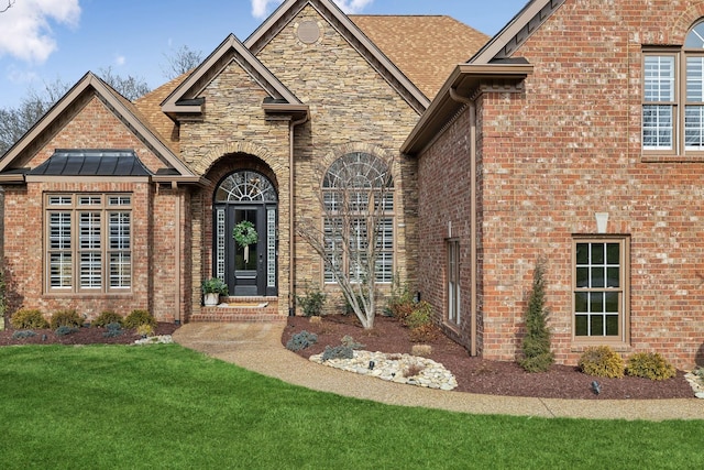 exterior space with brick siding, stone siding, and a front yard