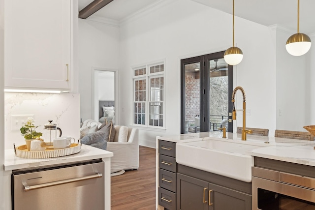 bar featuring a sink, beamed ceiling, wood finished floors, decorative light fixtures, and appliances with stainless steel finishes