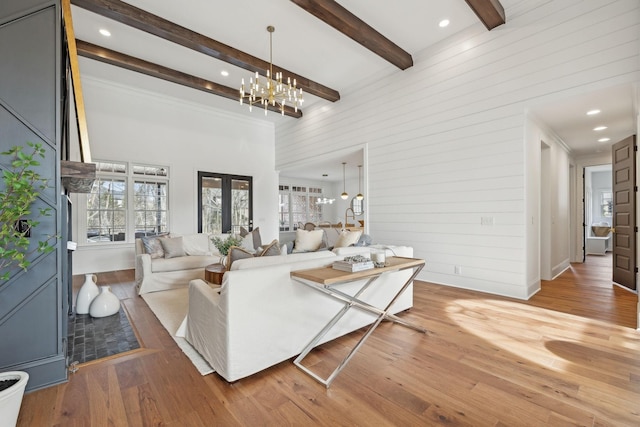living area featuring beamed ceiling, light wood-style flooring, and a notable chandelier