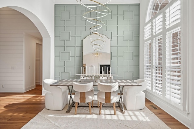 dining room with baseboards, arched walkways, wood finished floors, and plenty of natural light