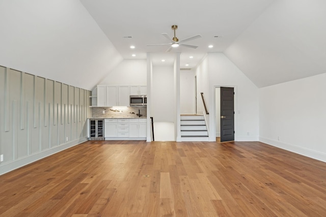 bonus room with light wood-style floors, beverage cooler, lofted ceiling, and stairway