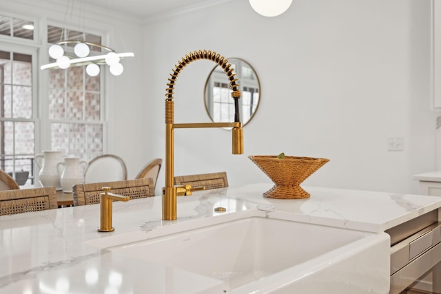 interior details with pendant lighting, light stone counters, and a sink